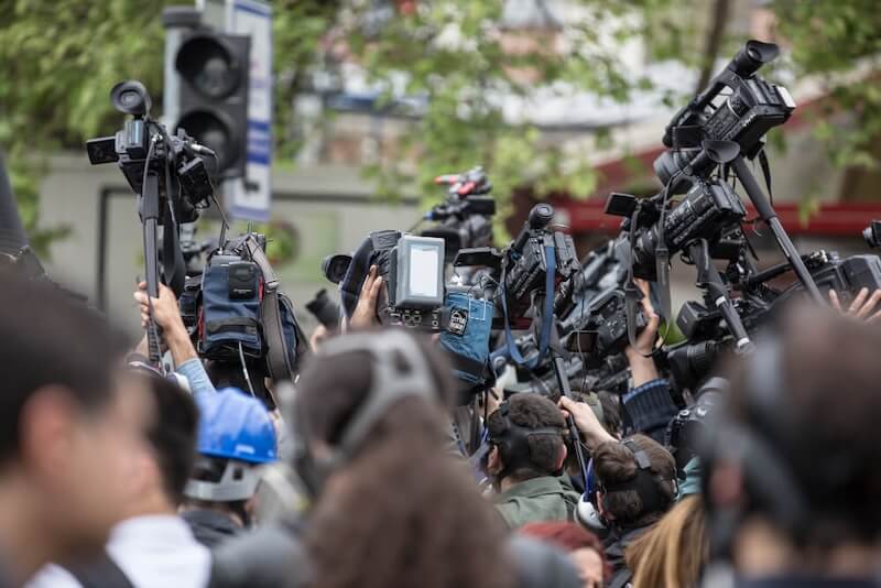 cameras and microphones pointed at interview during PR crisis meeting